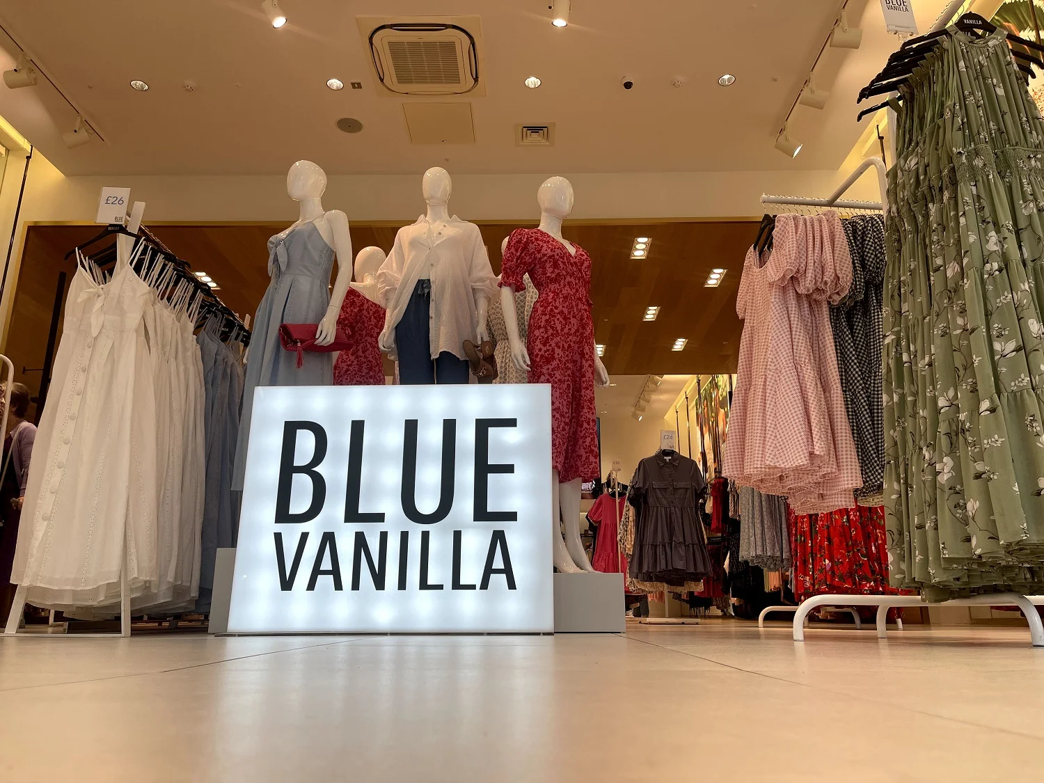 blue vanilla neon sign in the shop, mannequins and hangers with dresses